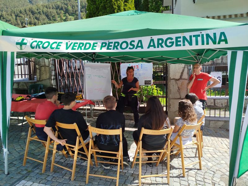 Un gruppo di ragazzi ascolta la spiegazione dei volontari sotto il gazebo