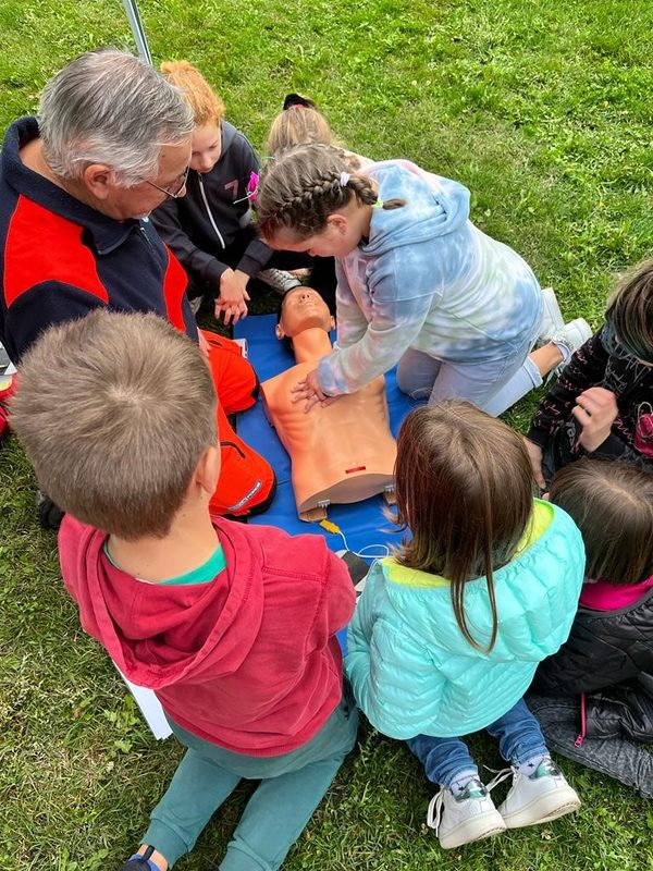 Bambini e un volontario intorno a un manichino durante una lezione di primo soccorso